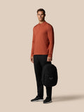 Male model holding Castore Core Backpack gunmetal by the side with logo visible on the front pocket.