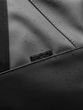 Close up of Core Holdall exterior in gunmetal black with water droplets on the PU surface and a padded strap