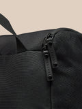Close-up of black Castore boot bag fabric showing a top strap and dual zipper pulls.
