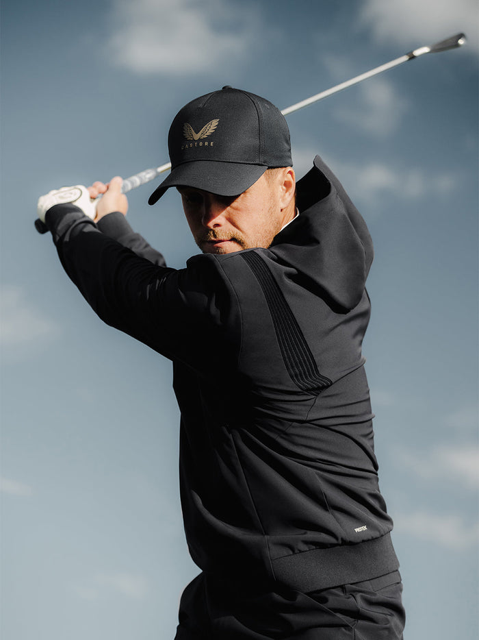 Male golfer wearing black Golf Pinnacle Performance Hoodie during a golf swing outdoors