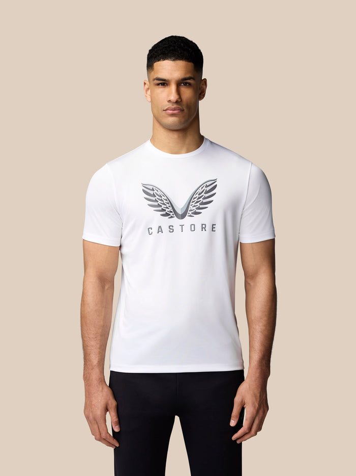 Close up of male model in white Castore graphic training T shirt with wings logo on chest.