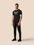 Rear three quarter view of male model in black Castore T shirt with short sleeves and Aertek branding at back hem