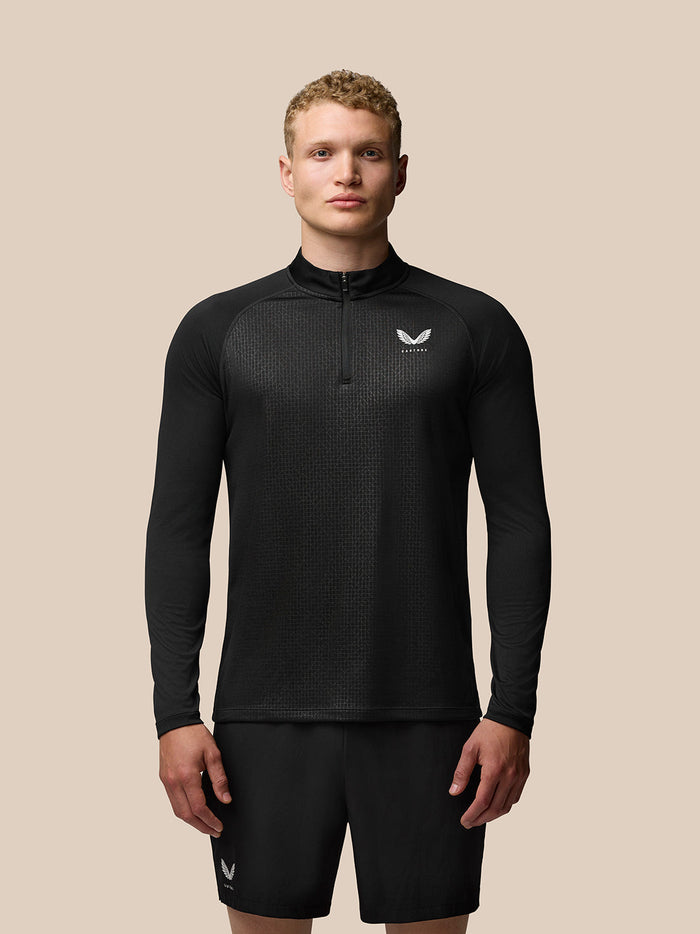 Full-body shot of a man wearing black Adapt Print Quarter Zip Top with all-over geometric pattern and Castore branding on chest
