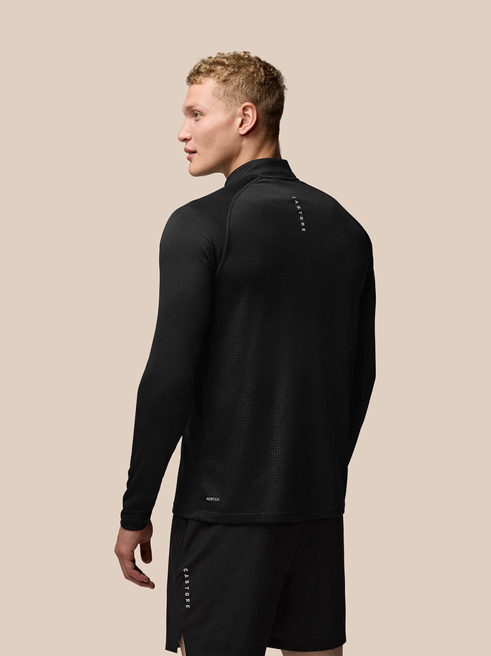 Back view of a man wearing black Adapt Print Quarter Zip Top with stand collar and all over geometric pattern.