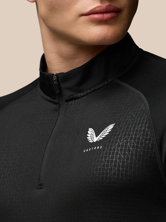 Close-up of black Adapt Print Quarter Zip Top with high collar and zip, featuring Castore logo on left chest.