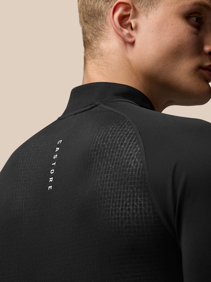 Back view of a man in black Adapt Print Quarter Zip Top showing geometric pattern and Castore branding along the back.