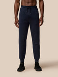 Front view of navy Flex Lifestyle Joggers on a model with a drawstring waistband, rib cuffs, and Castore branding on the left thigh.