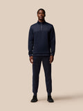 Full body shot of a man wearing navy Flex Lifestyle Joggers with a zip neck top on a beige background