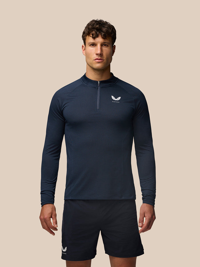 Male model wearing navy Apex Training Quarter Zip Top with stand collar and left chest Castore logo