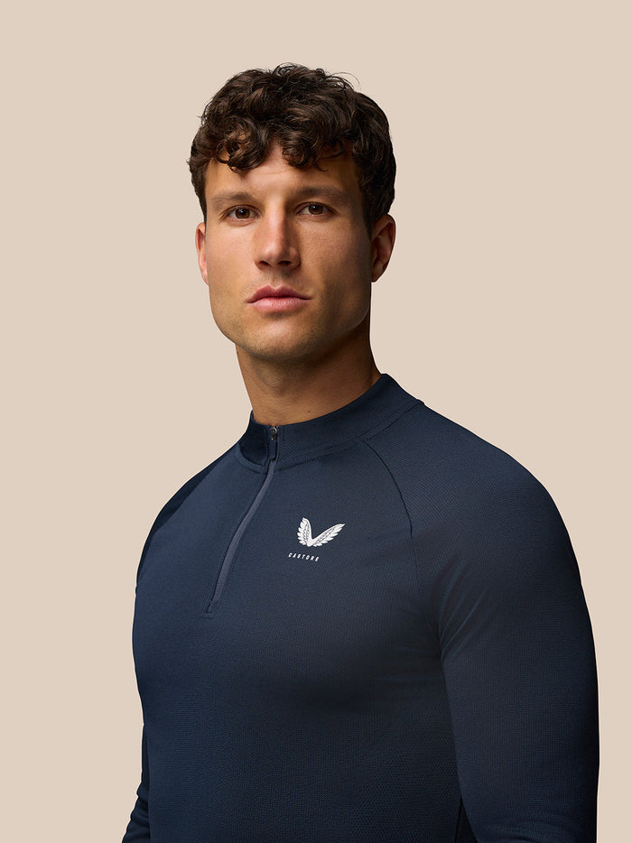 Male model wearing midnight navy Apex Long Sleeve Engineered Knit Quarter Zip Top showing the left chest logo.