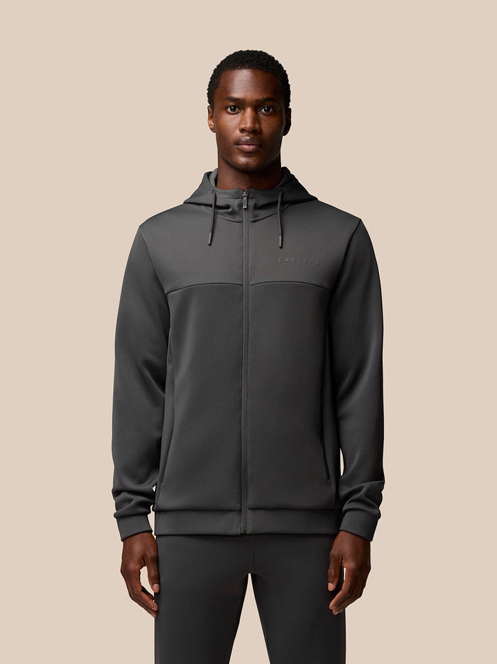 Male model wearing charcoal Flex Lifestyle Full Zip jacket with hood waterproof zips and Castore branding on chest