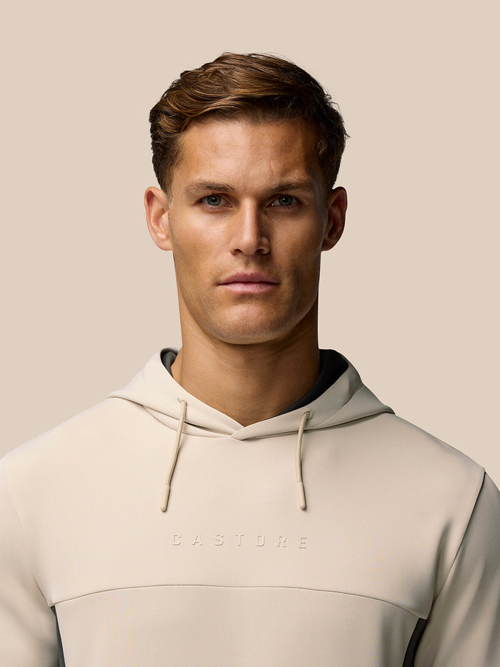 Male model wearing beige Flex Lifestyle Hoodie with drawstring hood and Castore branding on the chest.