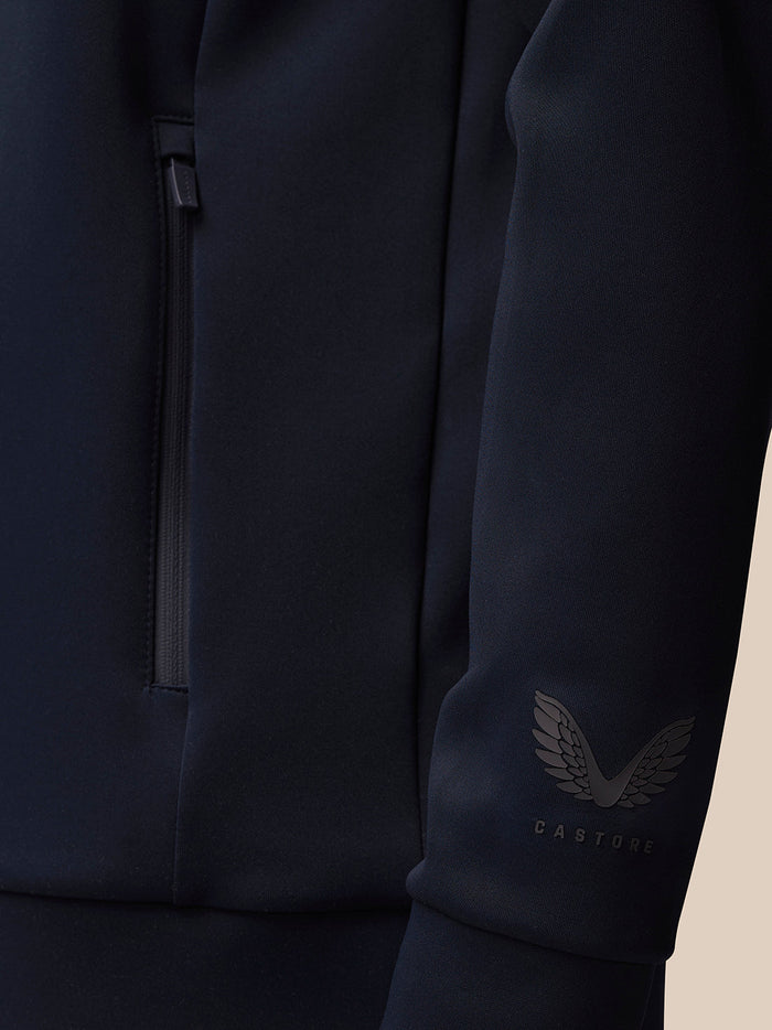 Detail of the navy quarter zip sleeve with the Castore wing logo near the cuff