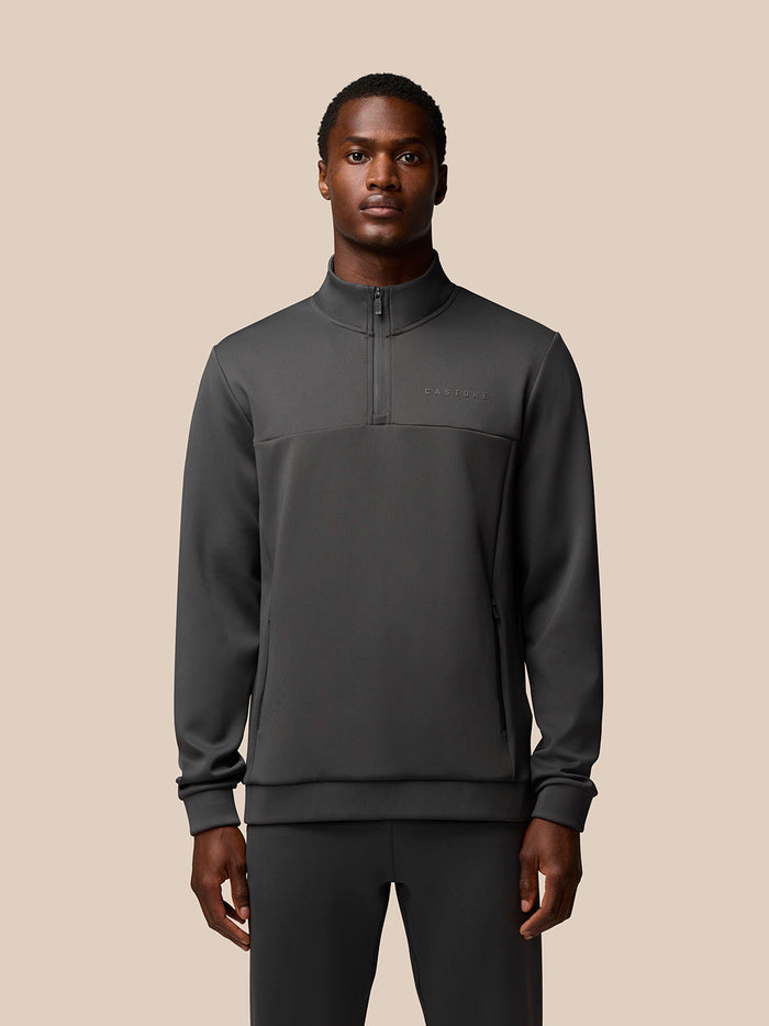 Male model wearing charcoal Flex Sweatshirt with quarter zip and zip pockets; Castore branding on left chest sleeve and hem