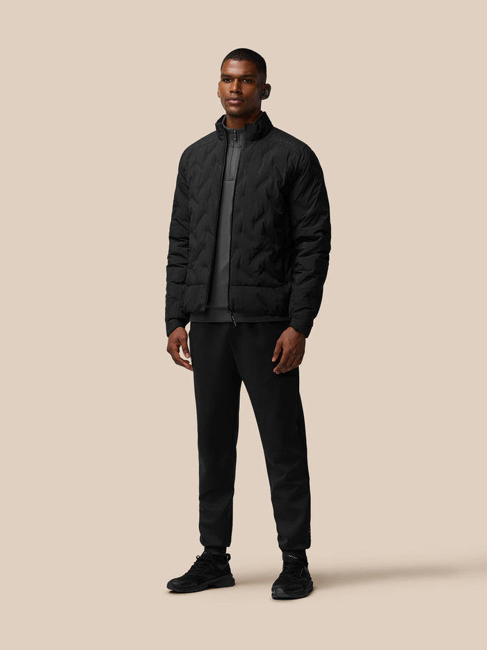 Full-body shot of a man wearing a black padded jacket with stand collar and zip front