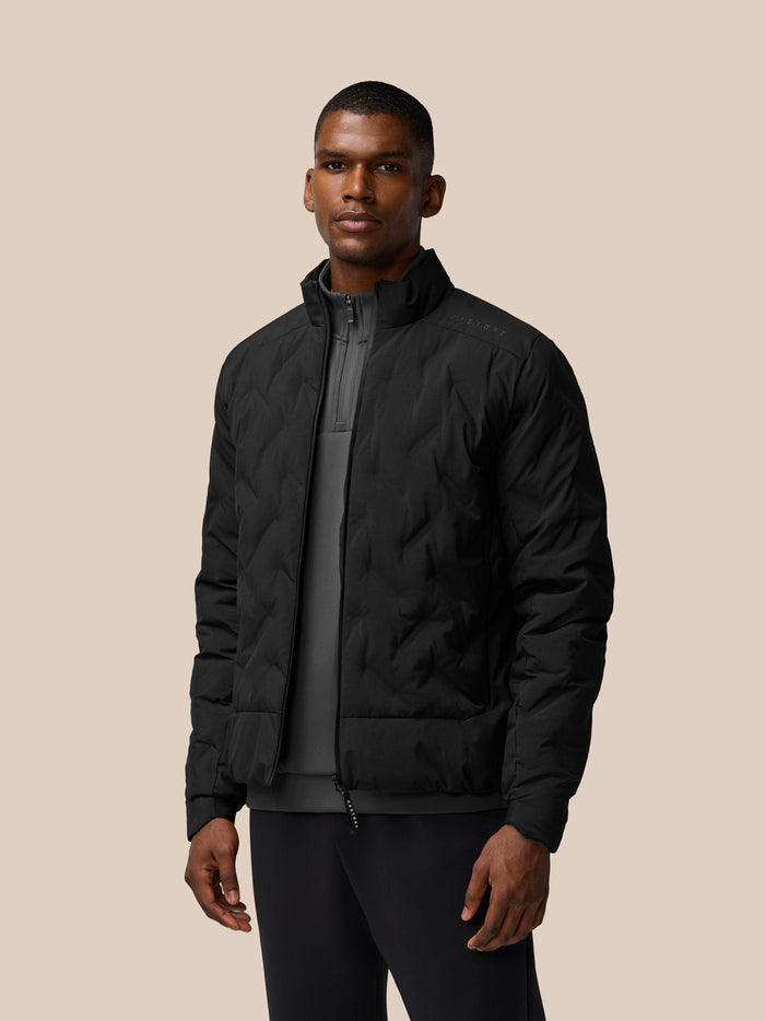 Front view of male model wearing black padded jacket with high collar and zip closure.