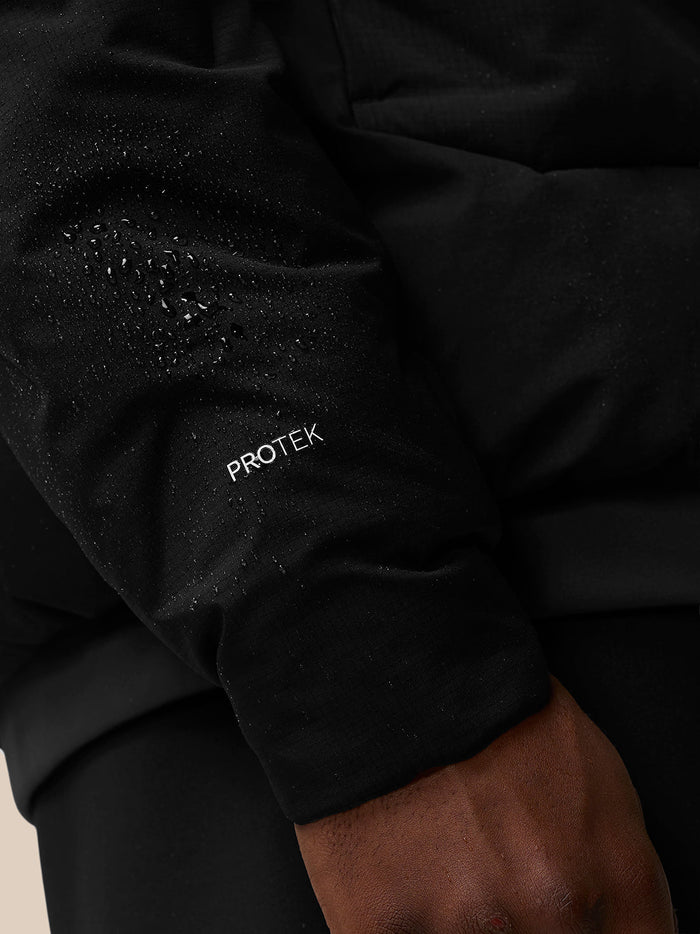Close-up of black padded jacket sleeve with Protek branding and water droplets.