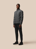 Male model wearing Quilts Lifestyle Jacket charcoal in full body view with zip-front closure and stand collar.