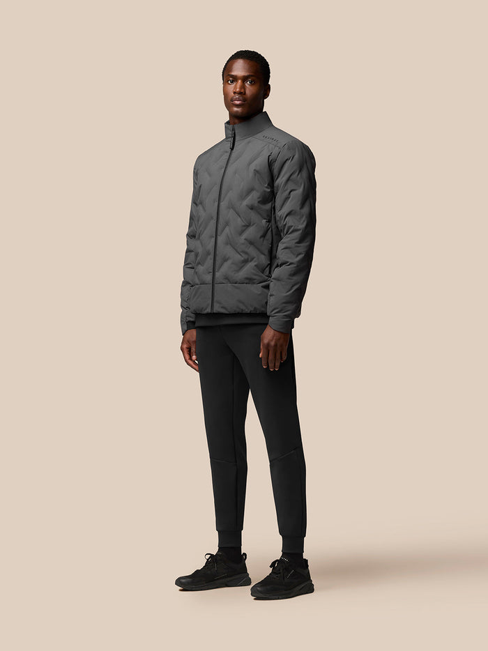 Male model wearing Quilts Lifestyle Jacket charcoal in full body view with zip-front closure and stand collar.