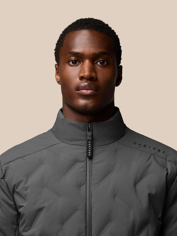 Close-up of Quilts Lifestyle Jacket charcoal on model showing zip-front and subtle Castore branding on shoulder.