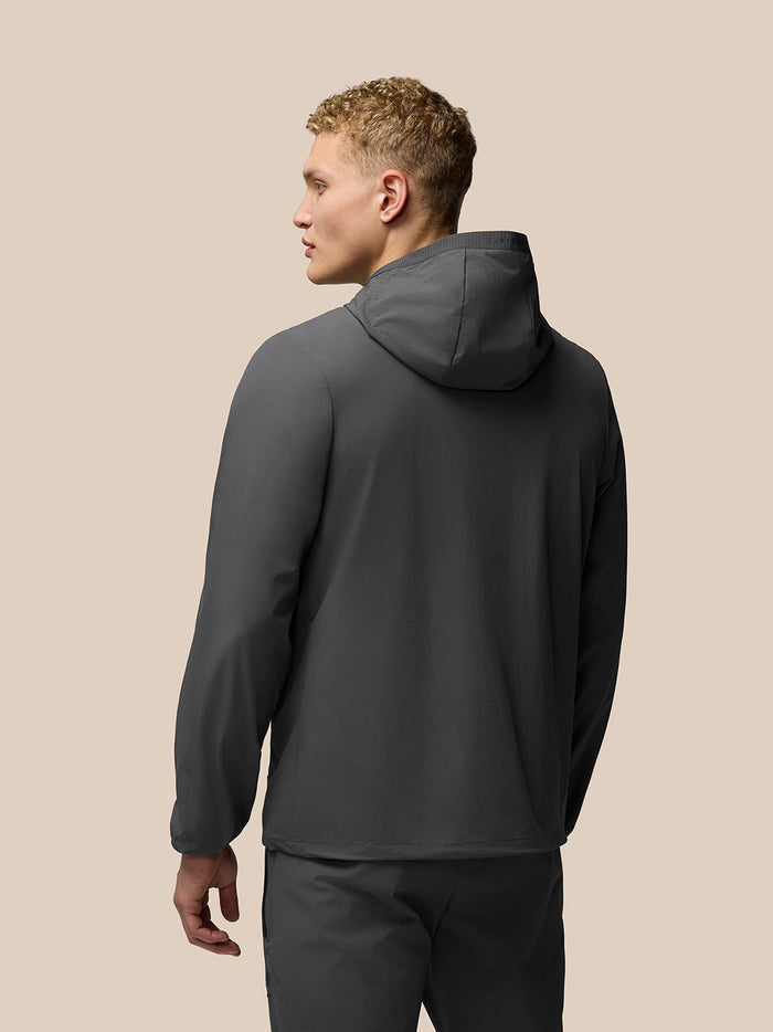 Side-back view of male model wearing charcoal Lightweight Flex Jacket with hood.