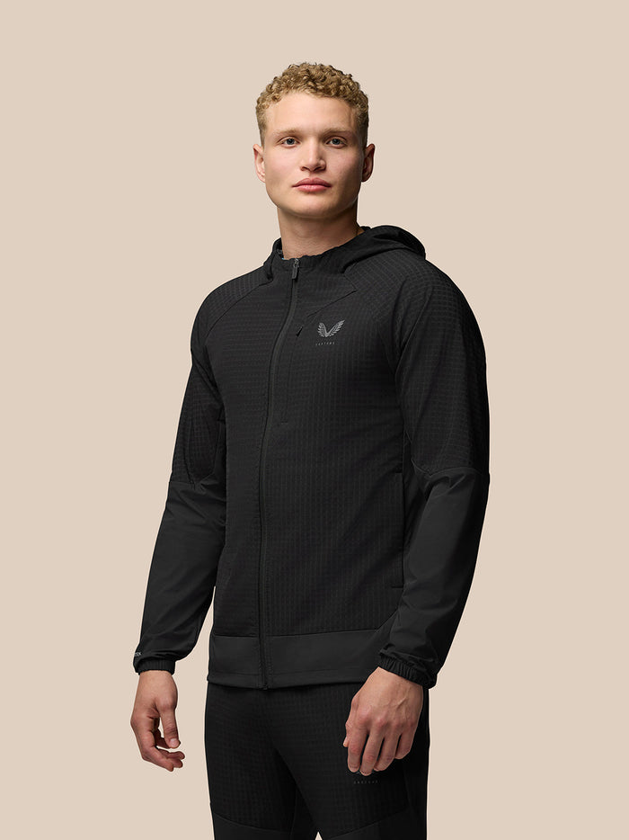 Male model wearing black Flex Winterised Jacket with hood and zip front and textured fabric.
