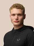 Front view of a model wearing a black Flex Winterised Jacket with hood, zipped up and chest logo visible.