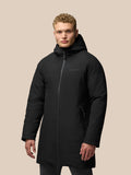 Full body view of a model in a black longline jacket with hood standing against a beige backdrop