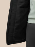 Close-up of the black longline jacket side showing a zip pocket and Castore branded zipper pull.
