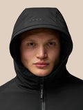 Model wearing a black hooded jacket with the hood up and a Castore zipper pull visible against a beige background