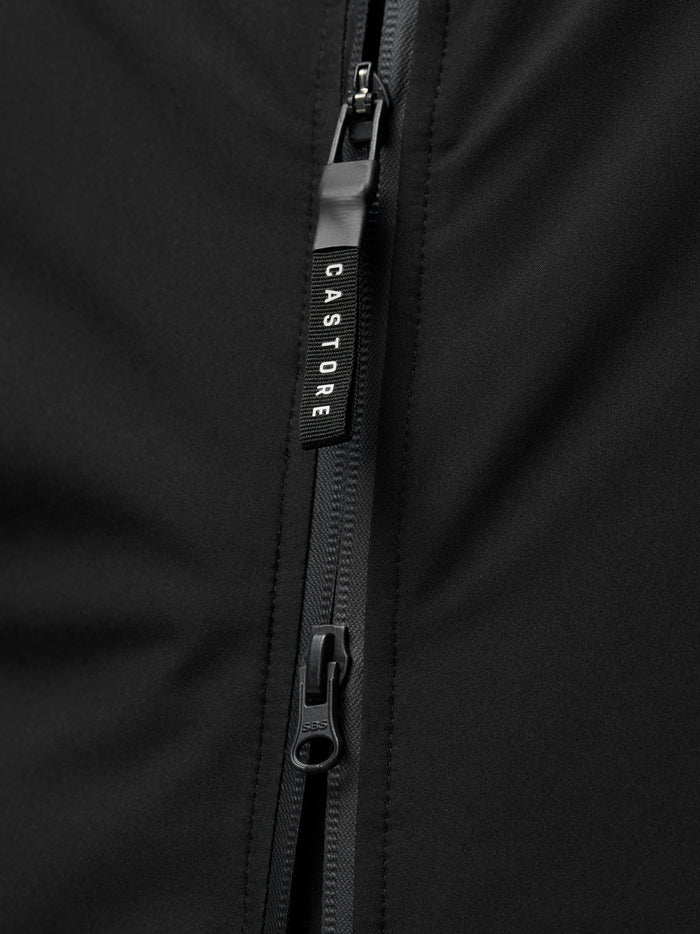 Close up of a black jacket zipper with a Castore branded pull against dark fabric