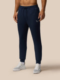 Male model in navy Travel Lifestyle Joggers with elastic drawstring waist and concealed zip pockets, Castore graphic on front.
