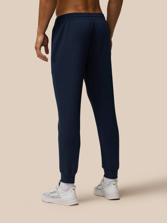 Back view of male model wearing navy Travel Lifestyle Joggers with elastic waistband and cuffed hems.