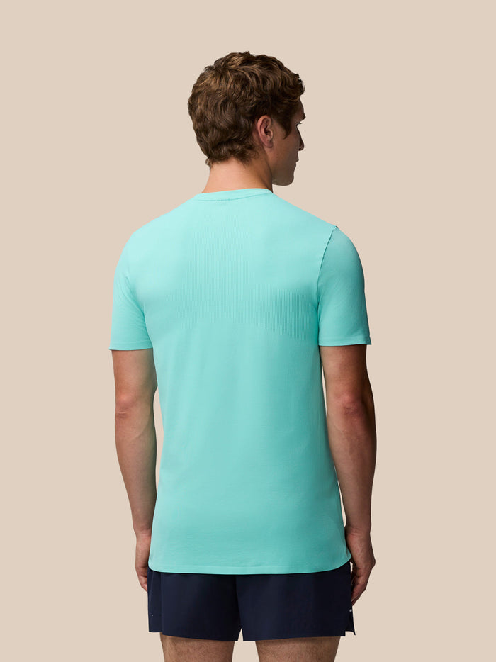 Back view of man wearing light aqua Zone Training T-Shirt with ribbed panels and navy shorts.