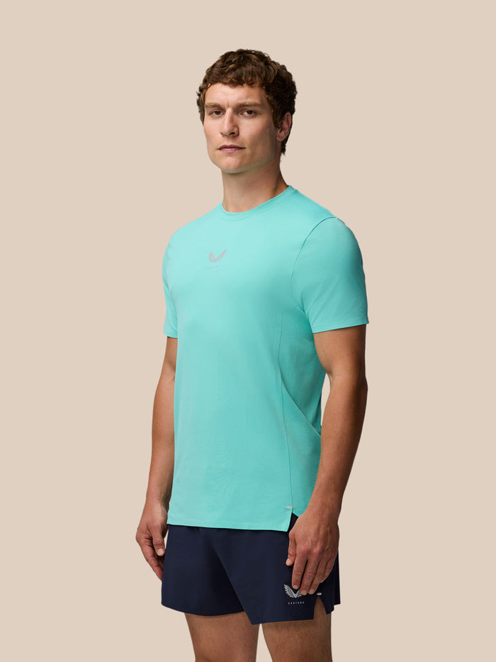 Full-length shot of a man in a light aqua Zone Training T-Shirt and navy shorts against a beige backdrop.