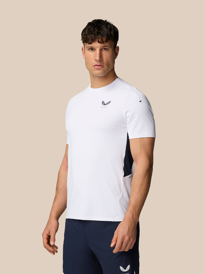 Side profile of a man in white Apex Training T-Shirt with navy side panel and Castore branding