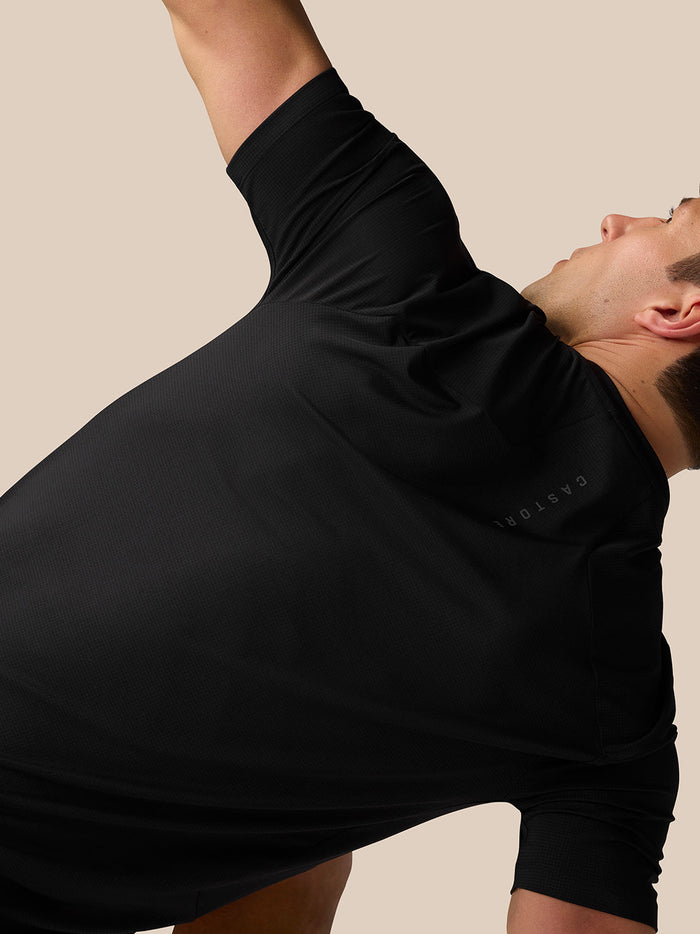 Close up of a man in black Apex Training T Shirt during a stretch, showing textured fabric and underarm area.