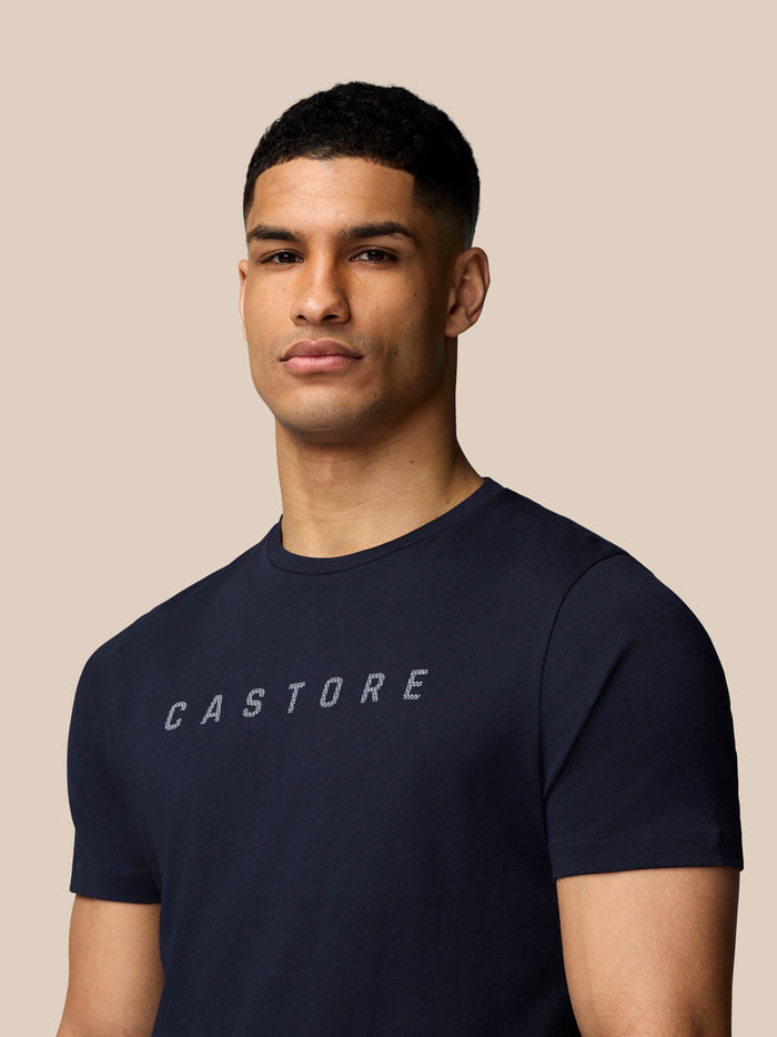 Close up of a man wearing navy Castore graphic T shirt showing the front design