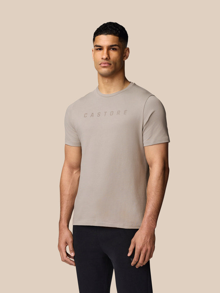 Male model wearing beige Rock Grey Castore graphic crew neck short sleeve T-shirt, front view.