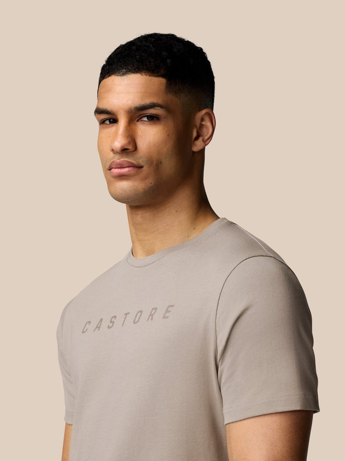 Close-up of a man wearing Rock Grey Castore graphic T-shirt highlighting the chest logo and crew neck