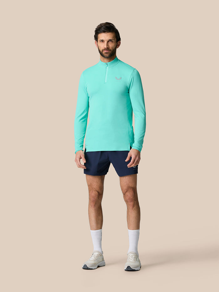 Full-body view of a man in light aqua Zone Training 1/4 Zip Top with navy shorts.