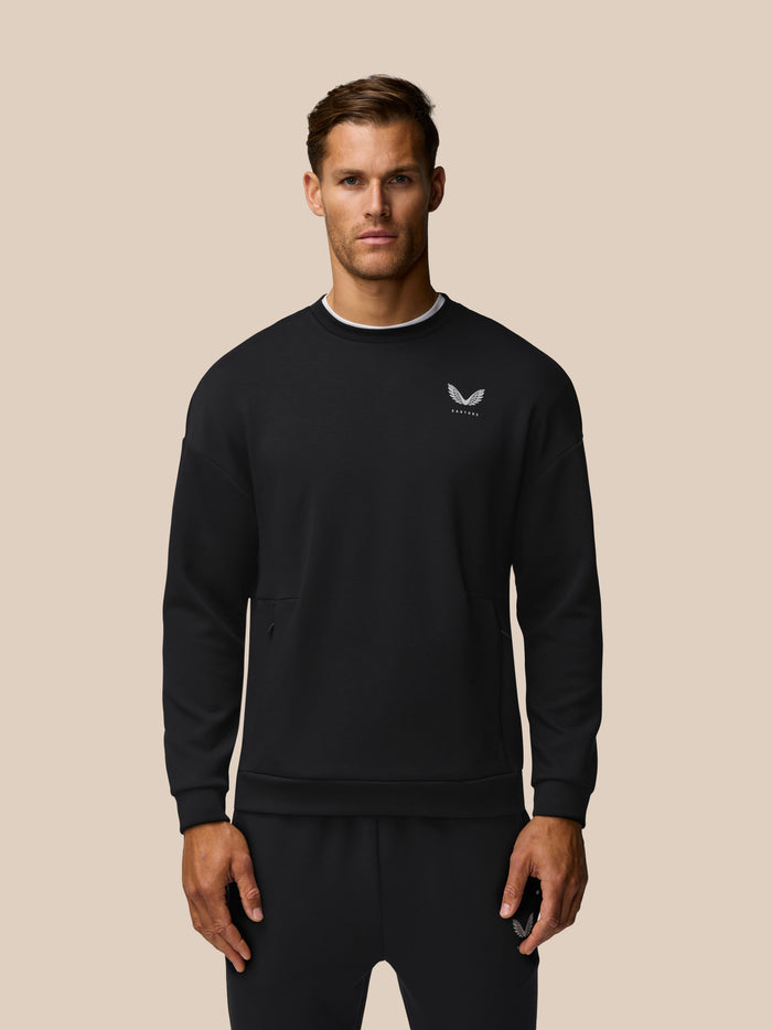 Front view of a man wearing a black crew neck sweatshirt with a small white wing logo on the chest