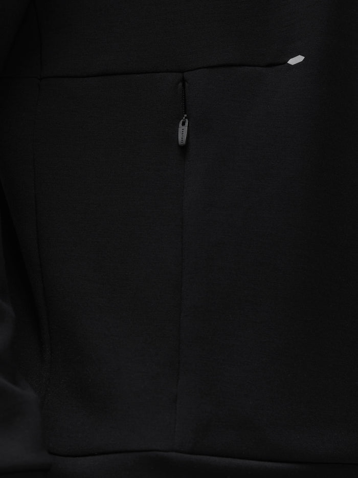 Close-up of the back center zipper on a black crew neck sweatshirt with a small logo near the shoulder.