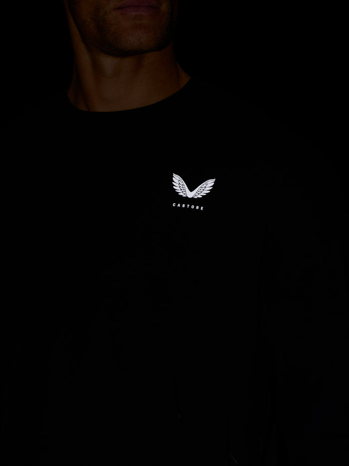 Man wearing black crew neck sweatshirt with white wing logo on chest