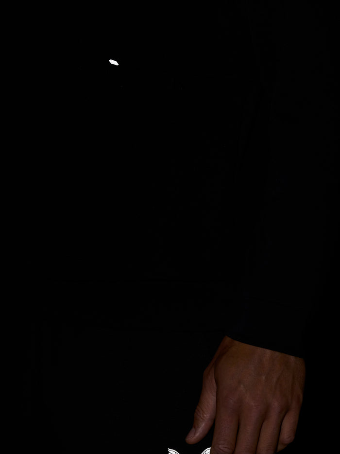 Close up of black crew neck sweatshirt showing white wing logo near lower chest