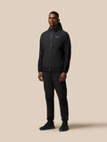 Male model wearing black Flex Winterised Woven Jacket with Castore logo on the chest, full-body shot.