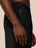 Close-up of left hip area on black Flex Winterised Woven Joggers showing a zipped pocket and textured panel.