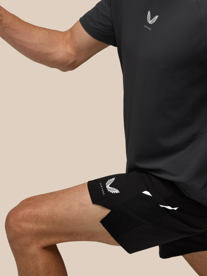 Close-up of a male model in a black athletic top with Castore logo and black shorts.