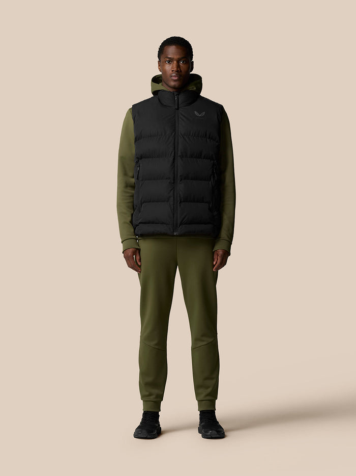Front view of a man wearing a black puffer gilet over an olive green hoodie.
