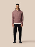 Front view of woman wearing mauve Adapt Lifestyle Hoodie with front pocket and CASTORE logo on chest
